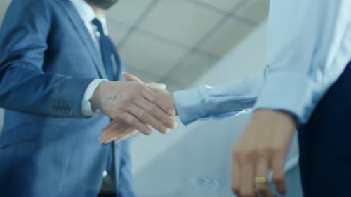Low Angle Close-up Shot of the Businessman with Businesswoman Shaking Hands with Emphasis on Handsh