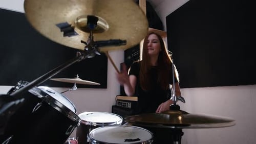 Young Woman Energetically Playing Drums in Music Studio