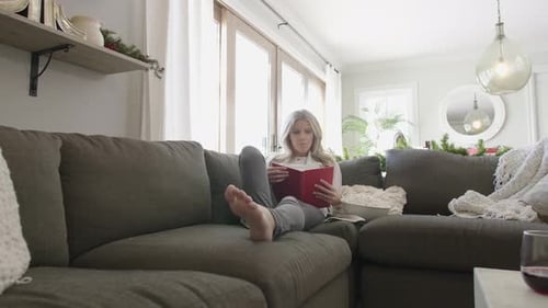Woman Reading Book on Couch in Living Room