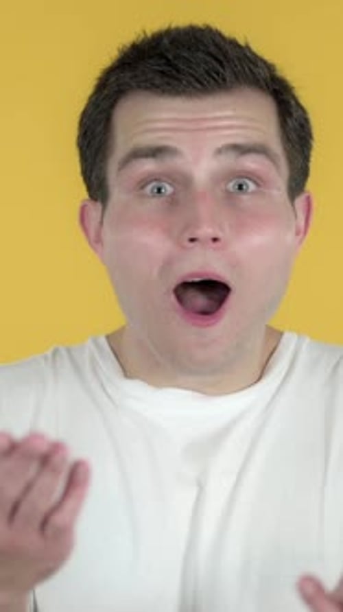 Surprised Man with Dark Hair Against Yellow Background