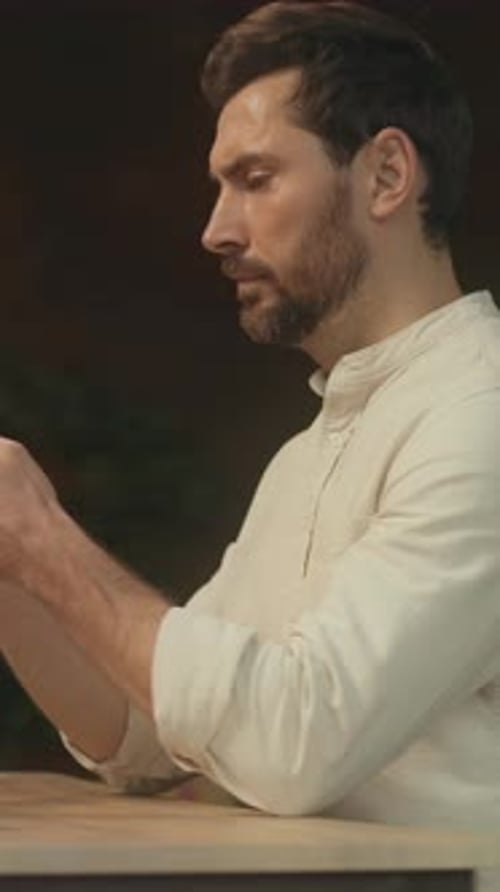 Man using Smartphone Device Sitting at Table Indoors