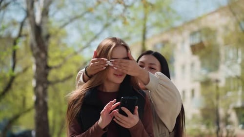 Caucasian Woman and Asian Friend Share Heartfelt Moment Outdoors Reunion in Park Where Friends