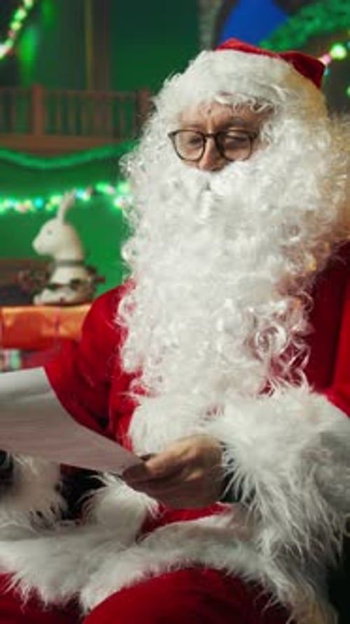 Vertical Video Happy Man Portraying Santa Claus Reading Letters From Kids Adjusting Hat