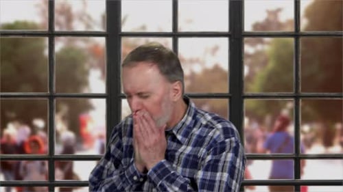 Man Coughing into Hands Near Window