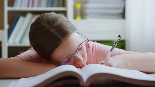 Girl Resting Head on Book Indoors