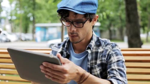 Man Uses Tablet on Bench in City Park