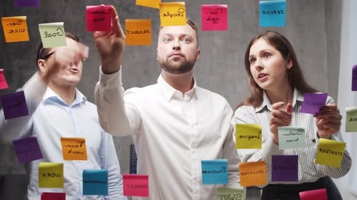 Team of Business People is Doing Brainstorm at a Meeting Using Stickers on the Glass Office Workers
