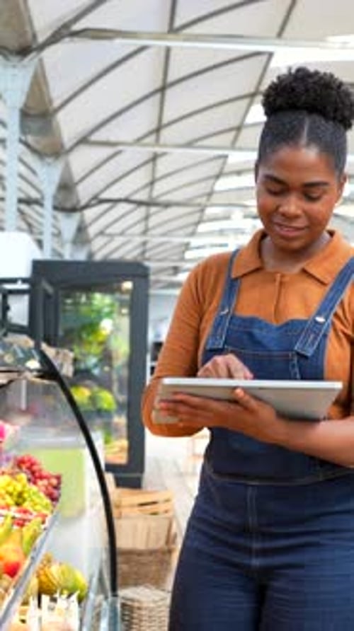 Grocer checking products and using digital tablet in supermarket