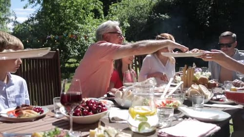 Happy family enjoying a festive summer garden party meal together outdoors
