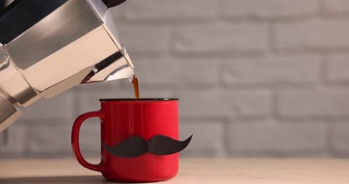 Feliz Día del Padre. Verter café de una cafetera de moka en una taza con bigote de papel
en madera