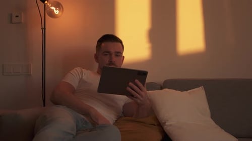Man Relaxing on Couch Using a Tablet
