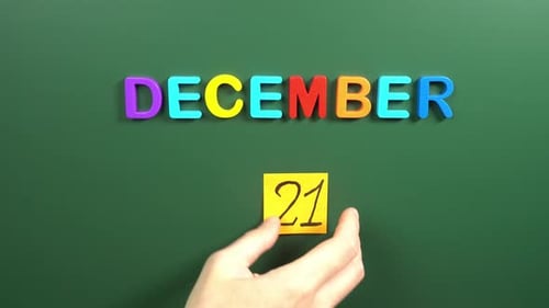 Hand sticking a sticker 21 December calendar day on school board. 21 date of December. Twenty first