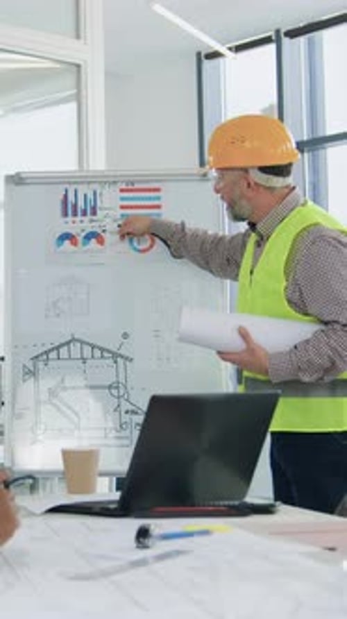 Construction Team Discussing Blueprints on Whiteboard in Office