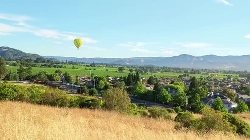 Pan right shot of Napa Valley wine region as hot air balloons floating in the background.