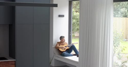 Man Playing Guitar in Bright Modern Home