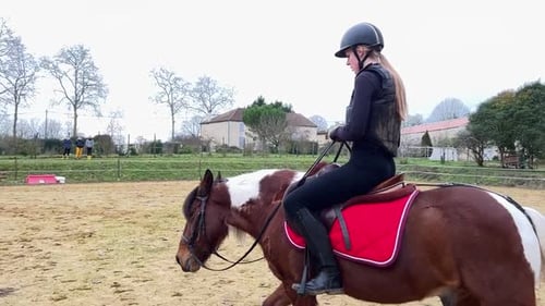 Jóquei feminina montando seu pônei no paddock