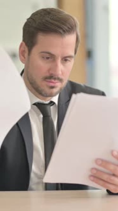 Businessman Reviewing Documents at Desk in Bright Office