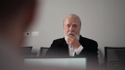 Serious Bearded Grayhaired Senior Businessman Talking to Unrecognizable Colleagues on Office
