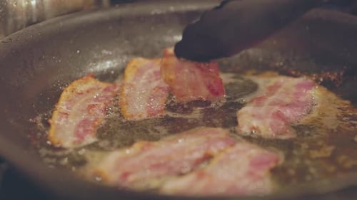 Flipping Bacon Sizzling In Pan While Cooking