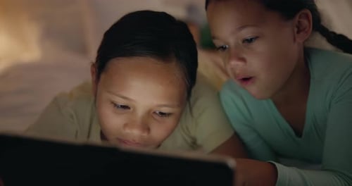 Two Girls Using Tablet at Night in Bed
