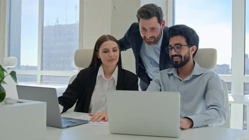Colleagues Working Together on Computers in Modern Office