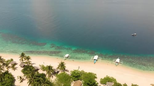 Aerial drone shot towards Paraw boats and a large shipwreck close to a beach, in beautiful, clear bl