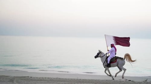 Man Riding Horse on Beach with Flag