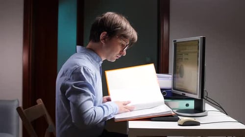 Accountant Working Late at Night in Office Reading Documents