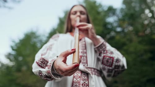 Hand of Woman Playing on Woodwind Wooden Flute Ukrainian Telenka or Tylynka on Forest Background