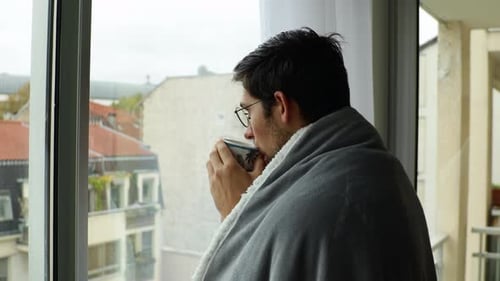 Young Adult Drinking Coffee by Window in Apartment