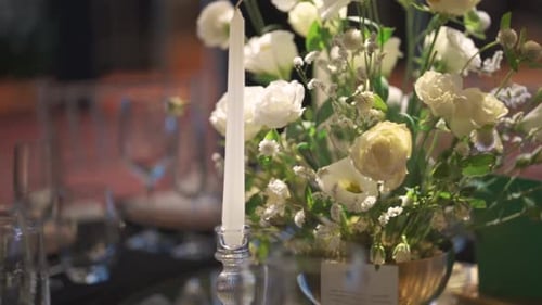 Ein Tisch mit einer Kerze und Blumen darauf. Der Tisch ist mit Glaswaren für ein Hochzeitsessen
gedeckt