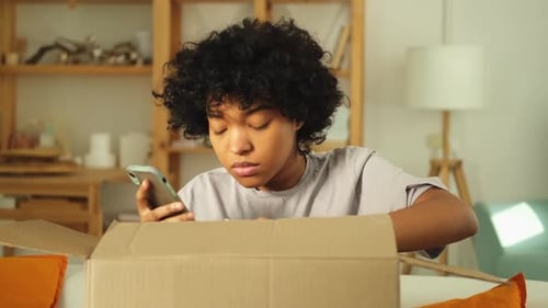Woman with Phone Looking into Delivery Box