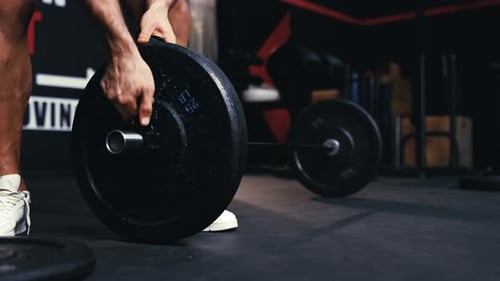Close up of athlete pre-workout preparing barbells for working out weightlifting