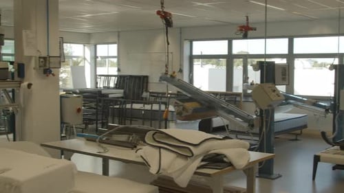 Pan over mattress making workshop with machines for testing and production