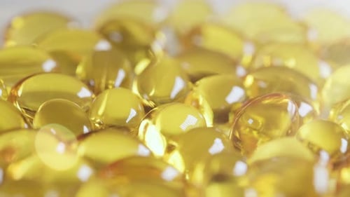 Pilules jaunes avec complément alimentaire oméga 3 tournant contre les rayons lumineux