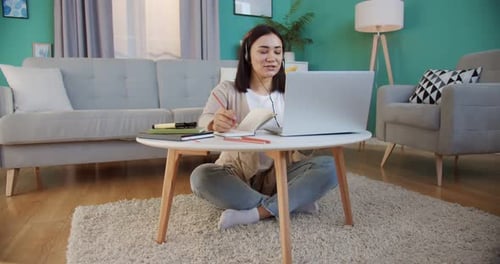 Woman Using Laptop, Talking and Taking Notes at Home