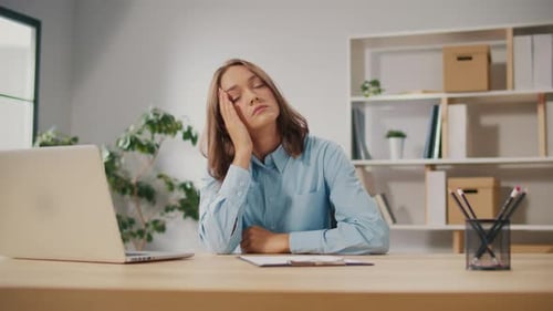 Portrait of a Tired Young Woman With a Headache Due to Overwork at the Computer