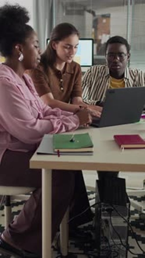 Team of Colleagues Collaborating on Laptop in Friendly Office Environment