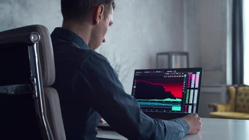 Kryptowährungshändler an seinem Arbeitsplatz vor einem Computer-Laptop-Monitor mit Aktienkorrektur