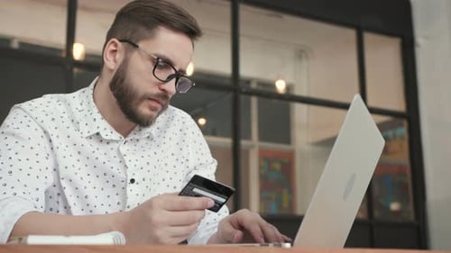 Mann zahlt online mit Bankkarte am Laptop