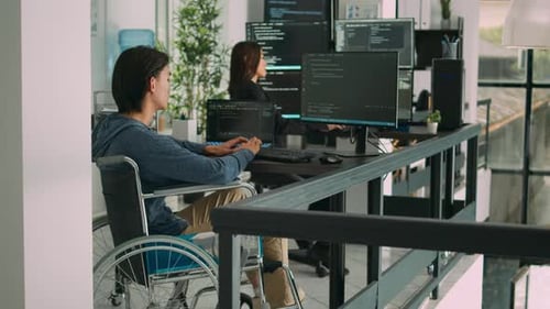 Focused Software Developer in Wheelchair Writing Server Code in Agency Data Room