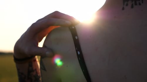 Close Up of Female Hand Taking Off Black Strap of Dress From Shoulder at Green Barley Meadow Arm of