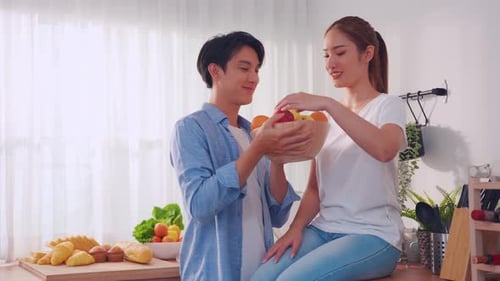 Smiling Couple Eating Fresh Fruit in Bright Kitchen