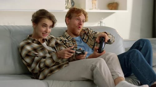 Excited Couple Play Video Games on Couch Together