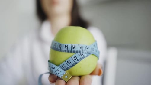 Woman Holding Apple Wrapped in Measuring Tape