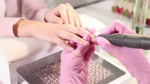 Professional manicurist working with client's nails in beauty salon, closeup