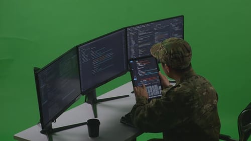Man Soldier Working With Tablet While Write Code With Multiple Computer Screens In Green Screen
