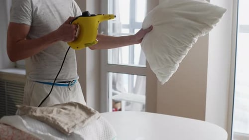 Man Steaming Pillow with Handheld Steamer