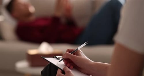 Psychologue professionnel prenant des notes sur un bloc-notes pendant une séance de thérapie avec un patient à l'intérieur