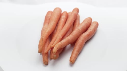 A bunch of fresh carrots slowly rotates.